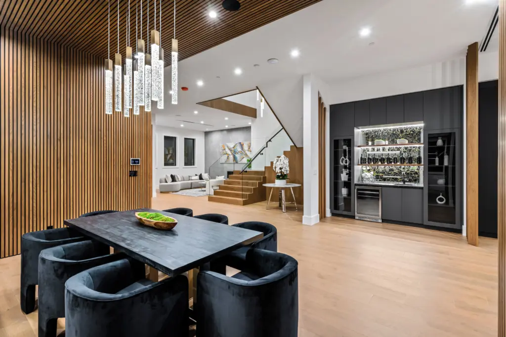 Image of a newly remodeled basement. Black chairs and table, staircase and a drink bar