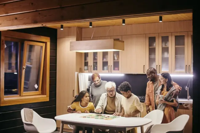 Multi generational and multi ethnic family sitting at table in basement playing a board game